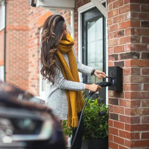 Women with yellow scarf charging blue electric vehicle.